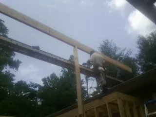 Carpenter setting a ridge beam over a new addition frame — Ice Dam Removal by Roofing Brothers in Wallisville