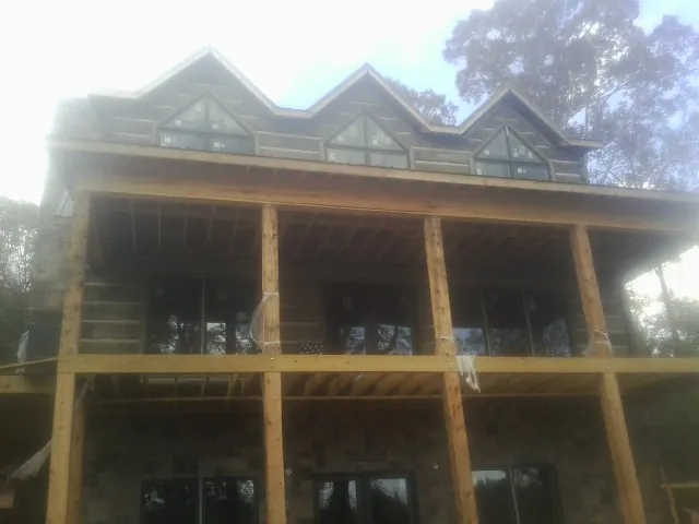 Dormers and porch framing on a large log home under construction — Roof Coating work by our crew in Wallisville