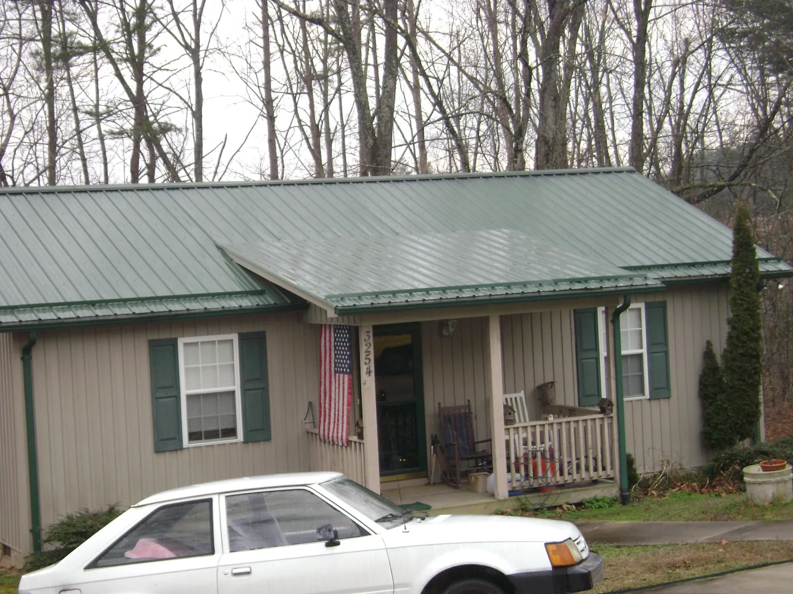 Green metal roof and front porch on a tan sided cottage in Wallisville