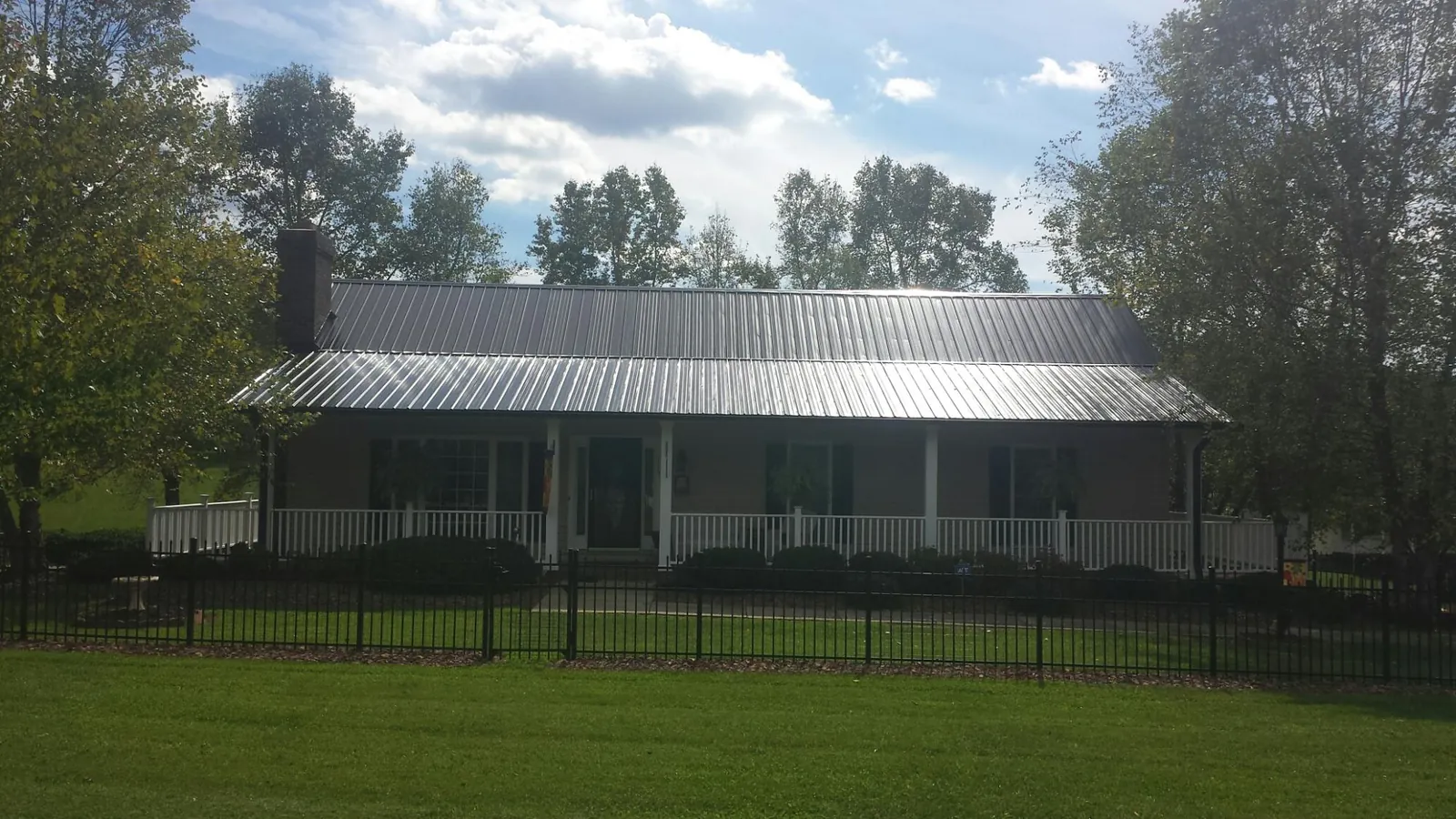 Gray metal roof on a brick ranch with a full width front porch — Gutter Guard Installation work by our crew in Wallisville
