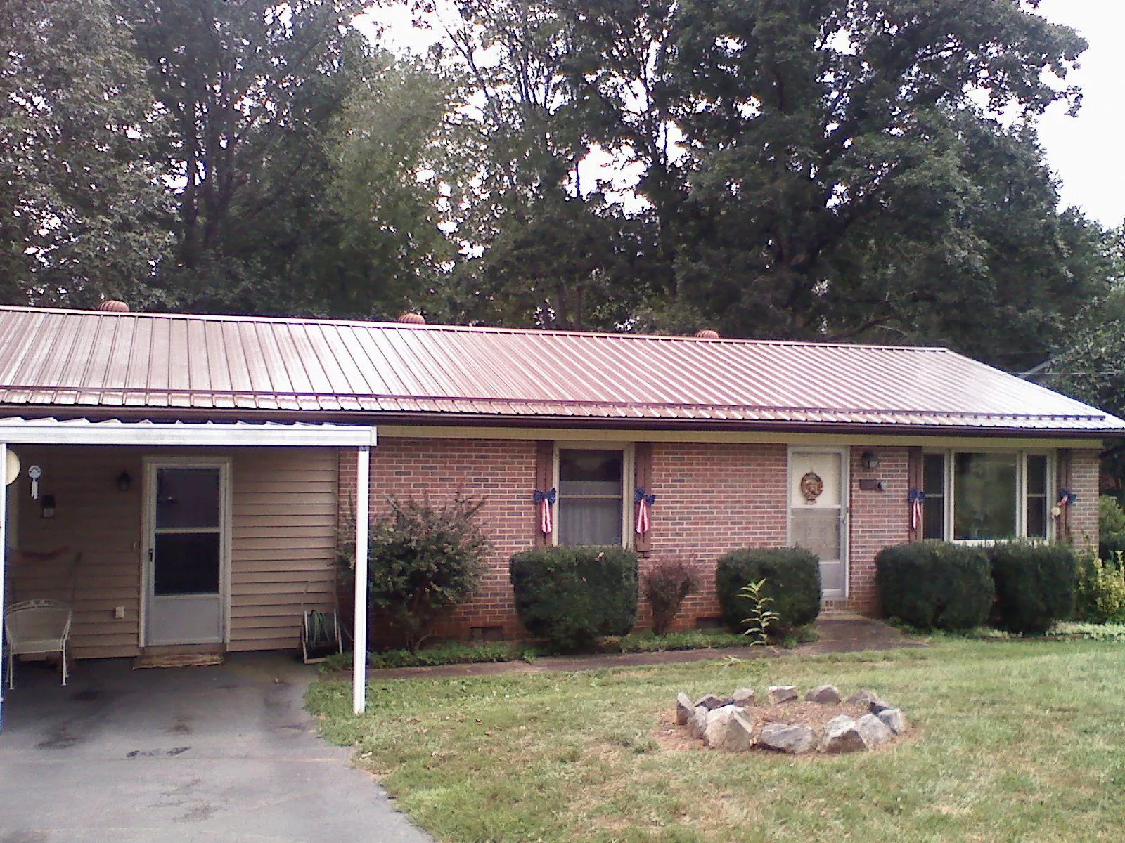 Bronze metal roof and carport on a brick ranch home — Roof Repair work by our crew in Wallisville
