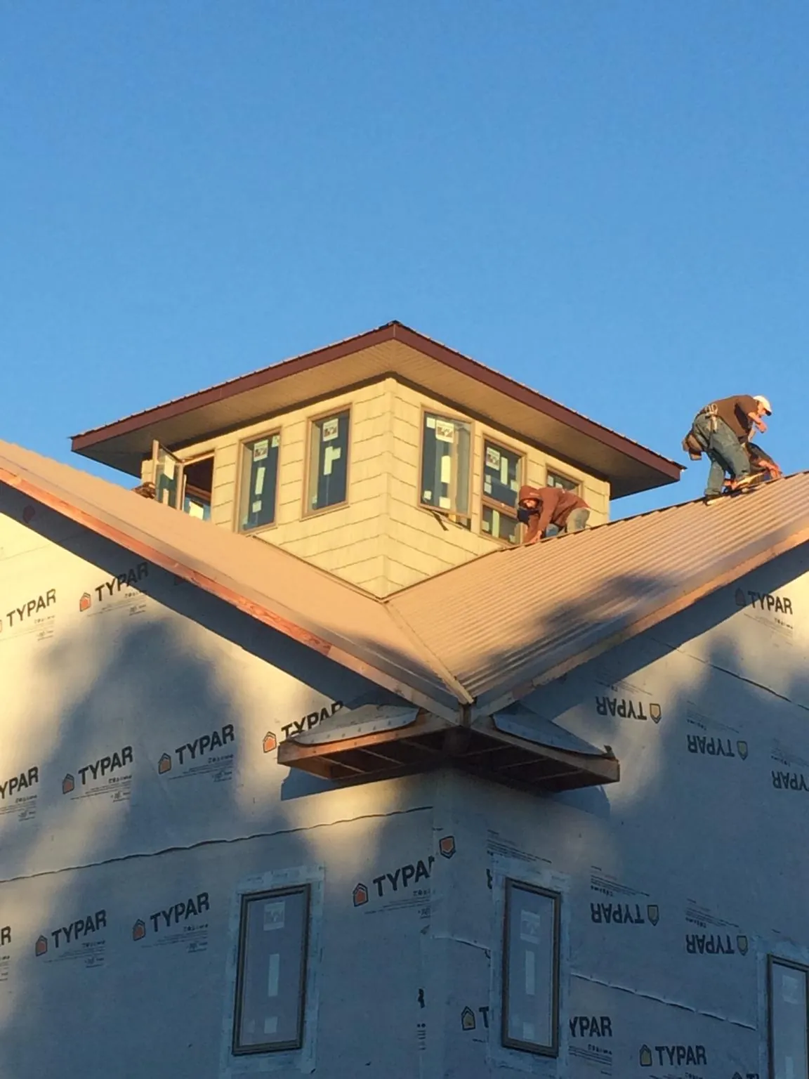 Roofers working around a rooftop cupola on a new metal roof at sunset — Roof Waterproofing in Wallisville by Roofing Brothers